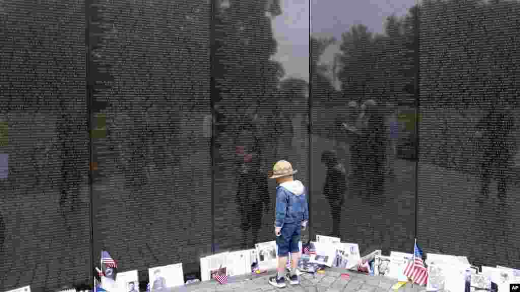 La pared que contiene grabados los nombres de veteranos de la Guerra de Vietnam, en Washington, es visitada por familias durante las celebraciones del Día de los Caídos.