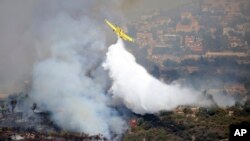 An aircraft drops water over a fire in Apesia, a semi-mountainous village near Limassol, southwestern Cyprus, Aug. 7, 2023. 