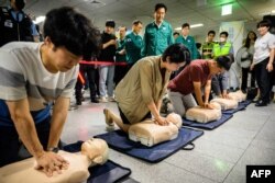 Wali Kota Seoul Oh Se-hoon (tengah atas) menyaksikan pelatihan CPR dengan menggunakan boneka peraga dalam rangka latihan pertahanan sipil melawan kemungkinan serangan artileri oleh Korea Utara, di stasiun kereta bawah tanah di Seoul, 23 Agustus 2023. (ANTHONY WALLACE / AFP)