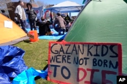 A sign calling attention to the conflict in Gaza rests against a tent, April 25, 2024, at an encampment on the Massachusetts Institute of Technology campus, in Cambridge, Mass.