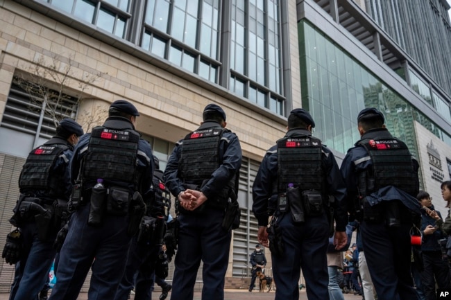 Police officers stand guard outside West Kowloon Magistrates' Courts, where activist publisher Jimmy Lai's trial is scheduled to open, in Hong Kong, Monday, Dec. 18, 2023. (AP Photo/Vernon Yuen)