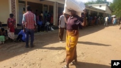 A woman carries maize meal from a U.N. World Food Program distribution center in Neno district, southern Malawi, March 24, 2024. Drought left millions facing hunger in southern Africa; Malawi declared a state of disaster earlier this year.