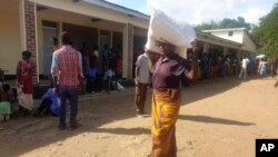 FILE - A woman carries maize meal from a United Nations World Food Program distribution center in Neno district, southern Malawi, March 24, 2024. Drought left millions facing hunger in southern Africa; Malawi declared a state of disaster this year.