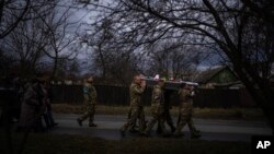 Ukrainian soldiers carry the body of Kostiantyn Kostiuk during his funeral in Borova, near Kyiv, Ukraine, Feb. 18, 2023. Kostiuk was a civilian who was a volunteer in the armed forces of Ukraine. He died Feb. 10, 2023, after being wounded in a battle against Russians.