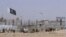 FILE - Pakistani and Taliban flags flutter on their respective sides while people walk through a security barrier to cross the Pakistan-Afghan border in Chaman, Pakistan, Aug. 18, 2021.