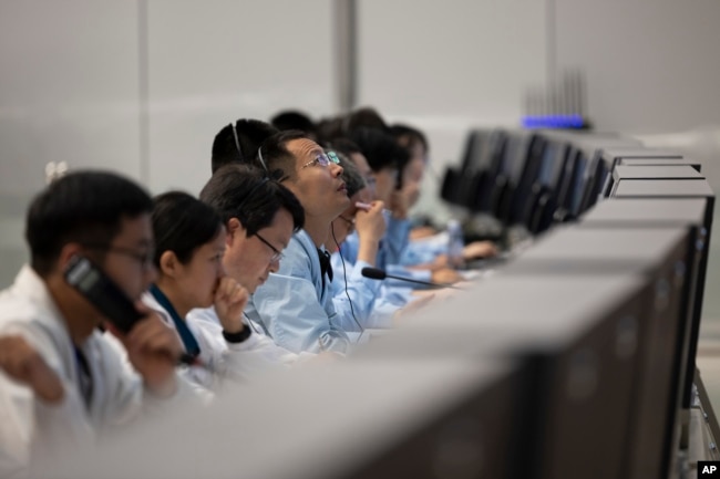 In this photo released by Xinhua News Agency, technical personnel work at the Beijing Aerospace Control Center (BACC) in Beijing, Sunday, June 2, 2024.(Jin Liwang/Xinhua via AP)