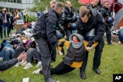 Seorang perempuan ditangkap polisi saat kelompok "Student Coalition Berlin" menggelar aksi unjuk rasa pro-Palestina di halaman teater universitas 'Freie Universität Berlin' di Berlin, Jerman, Selasa, 7 Mei 2024. (AP/Markus Schreiber)