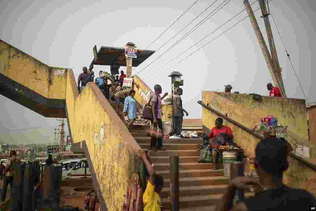 People cross a pedestrian bridge as street vendors sell their goods, in Anambra, Nigeria, Friday, Feb. 24, 2023. Nigerian voters headed to the polls Feburary 25, 2023 to select a new president following the second and final term of incumbent President Muhammadu Buhari.&nbsp;&nbsp;