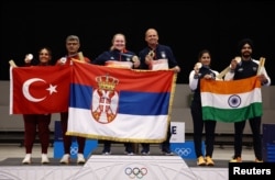 Osvajači srebrnih medalja Sevval Ilaida Tarhan iz Turske i Jusuf Dikec iz Turske, zlatne medalje Zorana Arunović iz Srbije i Damir iz Srbija i osvajači bronzanih medalja Manu Baker iz Indije i Sarabjot Sing iz Indije poziraju sa svojim nacionalnim zastavama.