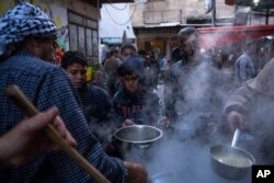 Warga Palestina, Walid Hattab membagikan makanan berbuka puasa berupa sup dan bubur gandum untuk penduduk yang kurang mampu (dok: AP)