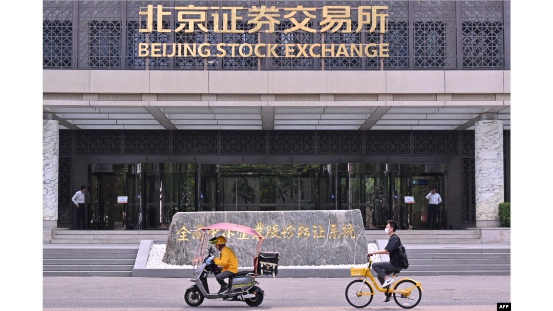 Sejumlah orang mengendarai motor melintas di depan Bursa Saham Beijing di Beijing, China, 9 Juli 2024. (Foto: Adek Berry/AFP)
