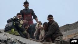 Emergency workers and volunteers pull a child from an apartment building damaged by a Russian military strike during Russia's attack on Ukraine in Sloviansk, Donetsk region, Ukraine, April 14, 2023.