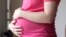 FILE - A pregnant woman stands for a portrait in Dallas, May 18, 2023. 