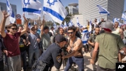 An Israeli police officer scuffles with protesters as they try to block a main road to protest plans by Prime Minister Benjamin Netanyahu's new government to overhaul the judicial system, in Tel Aviv, Israel, March 1, 2023.