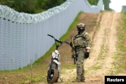 Petugas Unit Khusus Penjaga Perbatasan Latvia berpatroli di sepanjang pagar di perbatasan Latvia-Belarus dekat Robeznieki, Latvia 8 Agustus 2023. (REUTERS/Ints Kalnins)