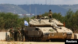 FILE - Israeli soldiers stand near to a tank near Israel's border with Lebanon in northern Israel, Oct. 16, 2023. Israel said on Nov. 3, 2024, that it launched a ground raid into Syria.