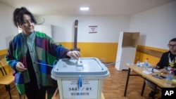 A woman casts her ballot at a polling station in the northern Serb-dominated part of ethnically divided town of Mitrovica, Kosovo, April 21, 2024. 