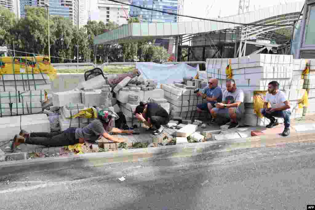 People take cover at a construction site during a rocket attack from the Palestinian Gaza Strip, on the city of Tel Aviv, amid the ongoing battles between Israel and the Palestinian group Hamas.