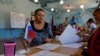 Избиратель перед членами избирательной комиссии на избирательном участке во время местных выборов в Донецке, контролируемая Россией Украина, 8 сентября 2023 года.