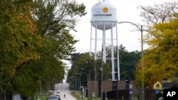 FILE - A pedestrian in Benton Harbor, Mich., crosses the street on Oct. 22, 2021, near the city's water tower. The U.S. is taking steps to better protect public drinking water and sewer systems from cyberattacks. 