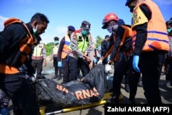 Anggota BASARNAS membawa kantong mayat saat melakukan operasi pencarian pengungsi Rohingya yang hilang di dekat Calang, Aceh Barat, pada 23 Maret 2024. (Foto: AFP/Zahlul AKBAR)