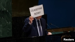 Palestinian U.N. envoy Riyad Mansour holds up a sign during a plenary meeting in the General Assembly Hall at U.N. headquarters in New York, Jan. 9, 2024.