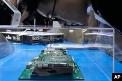 A visitor examines a computer chip set at the booth for Chinese semiconductor and chip developer Kunlunxin during the World AI Conference in Shanghai on July 5, 2023.