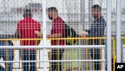 Migrants hold documents as they wait for their appointments to be processed by U.S. immigration officials on the McAllen-Hidalgo International Bridge, May 12, 2023, in Hidalgo, Texas.