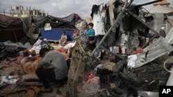 Pengungsi Palestina memeriksa tenda mereka yang hancur akibat pengeboman Israel, di samping fasilitas UNRWA di sebelah barat kota Rafah, Jalur Gaza, Selasa, 28 Mei 2024. (Foto: AFP)