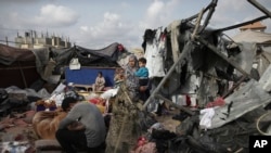 Raseljeni Palestinci pregledaju svoje šatore uništene izraelskim bombardiranjem, pored objekta UNRWA zapadno od grada Rafah, Pojas Gaze, utorak, 28. maja 2024