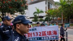 Polisi menyaksikan pengunjuk rasa berjalan di dalam garis penjagaan dengan mengenakan nomor tag saat unjuk rasa di Hong Kong, 26 Maret 2023. (Foto: AP)