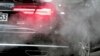 FILE - A luxury car is surrounded by exhaust gases as it is parked with a running engine in front of the Chancellery in Berlin, Germany, Nov. 20, 2019.