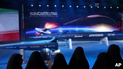 Women look at a Fattah missile in a ceremony in Tehran, Iran, June 6, 2023. Iran is claiming that it's created a hypersonic missile capable of traveling at 15 times the speed of sound. 