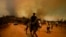 FILE - A resident flees an encroaching forest fire in Vina del Mar, Chile, Feb. 3, 2024.