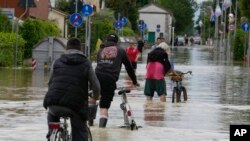People pedal in a flooded street in Barbiano di Cotignola, Italy, May 18, 2023.