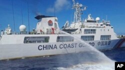 (FILE) A Chinese coast guard ship uses water canons on a Philippine Coast Guard ship in the South China Sea.