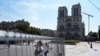 People watch Notre Dame cathedral from outside the security zone set up for the Olympic Games in Paris, July 18, 2024. 