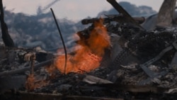 Varias casas ardieron el lunes cuando un incendio forestal de rápido avance quemó una comunidad en la ladera de una colina de California.