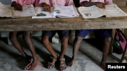 FILE - Students read books at a primary school on Ghoramara Island, India, Nov. 16, 2018. A teacher at a private elementary school in the state of Uttar Pradesh has come under fire for allegedly asking students to slap a Muslim classmate.