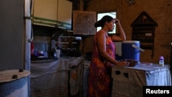 FILE - Gladys leans over a plastic containers that she fills daily with water through a community-made pipe system in the low-income neighborhood of Petare, in Caracas, Venezuela, May 12, 2023. (REUTERS/Gaby Oraa)