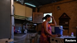 Gladys leans over a plastic containers that she fills daily with water through a community-made pipe system in the low-income neighborhood of Petare, in Caracas, Venezuela, May 12, 2023.