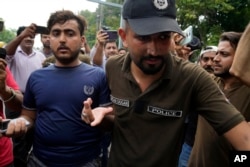 A police officer detains a supporter of Pakistan's former Prime Minister Imran Khan in Lahore, Pakistan, on Aug. 5, 2023.