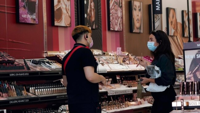 FILE - A worker, at left, tends to a customer at a cosmetics shop on Thursday, May 20, 2021, in Los Angeles.