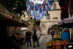 People talk under election banners of Turkish CHP party leader and Nation Alliance's presidential candidate Kemal Kilicdaroglu in Istanbul, Turkey, May 23, 2023.