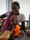 FILE - A mother sits with her malnourished baby at a hospital run by Medicines Sans Frontieres (Doctors Without Borders) in Old Fangak in Jonglei state, South Sudan, Dec. 28, 2021. Thousands of people in the country still depend on aid from the outside.