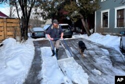 Harold Merrimont shovels heavy, wet snow alongside his dog in Plainfield, Vermont, Jan. 10, 2024.