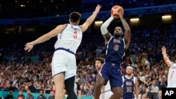 LeBron James, right, of the United States, shoots as Filip Petrusev, of Serbia, defends in a men's basketball game at the 2024 Summer Olympics, in Villeneuve-d'Ascq, France, July 28, 2024. 