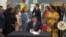 In this screenshot from a livestream broadcast by the State of Illinois, Gov. J.B. Pritzker signs a bill, June 12, 2023, at Harold Washington Library's Thomas Hughes Children's Library in downtown Chicago. (State of Illinois via AP)