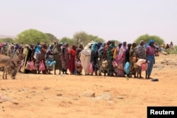 Sudanese refugees stand in line to receive food aid near the border between Sudan and Chad, in Koufroun, Chad, May 9, 2023.
