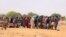 FILE - Sudanese refugees stand in line to receive food aid near the border between Sudan and Chad, in Koufroun, Chad, May 9, 2023.